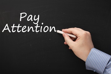 Writing the phrase Pay Attention on a Blackboard