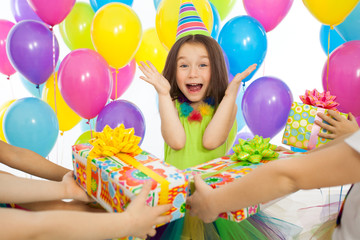 Joyful little kid girl receiving gifts at birthday party