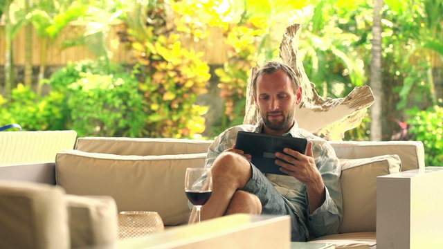 Young Man Sitting With Tablet On Sofa At Home