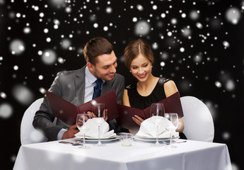 smiling couple with menus at restaurant