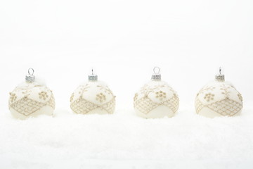 Many white christmas baubles in line on snow