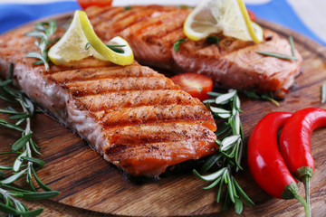 Grilled salmon with spices on cutting board on wooden