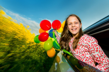 Laughing long-haired young girl with colourful balloons