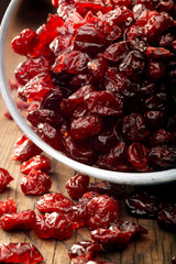 Dried cranberries in a glass bowl on wooden background