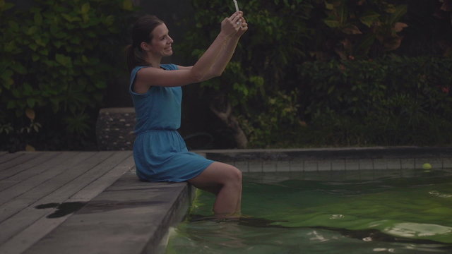 Woman taking selfie on the edge of swimming pool