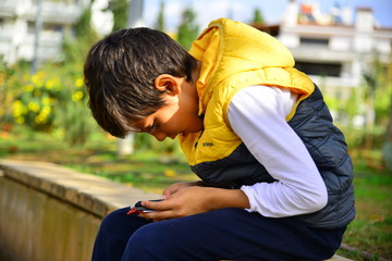 Boy playing with smart phone in the park