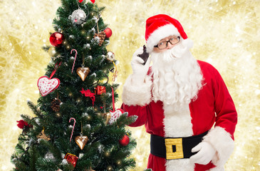 santa claus with smartphone and christmas tree