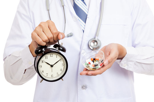 Asian male doctor show a clock and pills