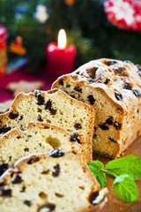 Sliced fruitcake with raisins and mint leaf on christmas backgro