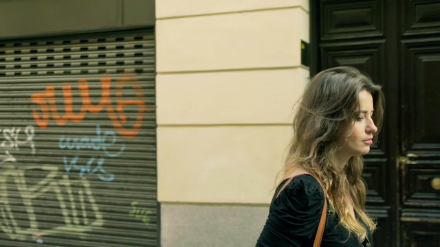 Woman walking on the street with graffiti on walls, steadycam