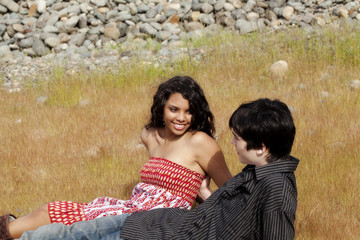 Teen Couple Sitting In Grass Outdoors Together