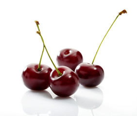 Four cherries close-up on white background with reflection