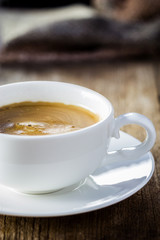 Composition with white cup of coffee on wooden table
