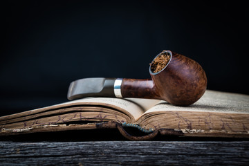 Closeup of smoking pipe on the opened old book