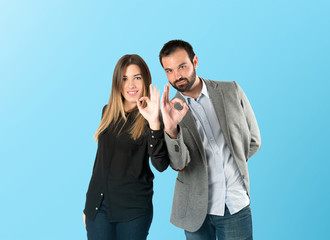 Couple making Ok sign over blue background