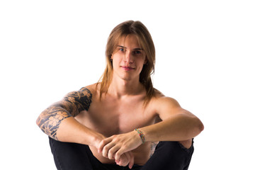 Attractive young man with long hair shirtless, sitting, isolated