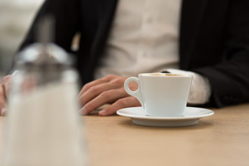 Zuckerstreuer auf Tisch vor Geschäftsmann Fokus auf Kaffee