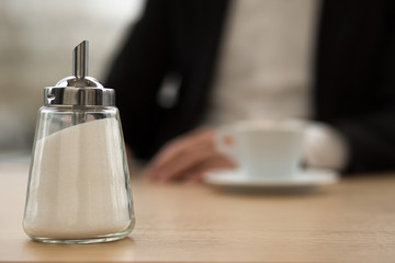 Zuckerstreuer auf Tisch vor Geschäftsmann mit Kaffee