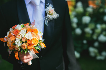 Groom is holding bridal bouquet