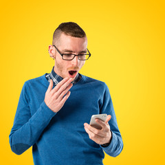 Men with phone surprised over yellow background