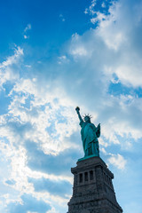 Fototapeta na wymiar The Statue of Liberty against a blue sky and clouds