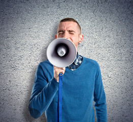 Redhead man shouting by megaphone over textured background
