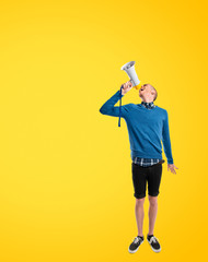 Redhead man shouting by megaphone over yellow background