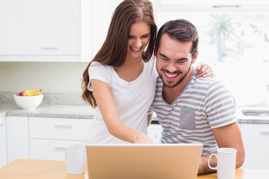 Young couple smiling and using laptop