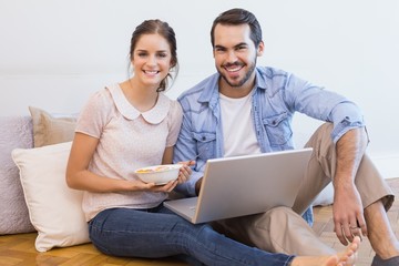 Cute couple sitting on floor using laptop