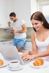 Obraz na płótnie Canvas Young woman using laptop at breakfast