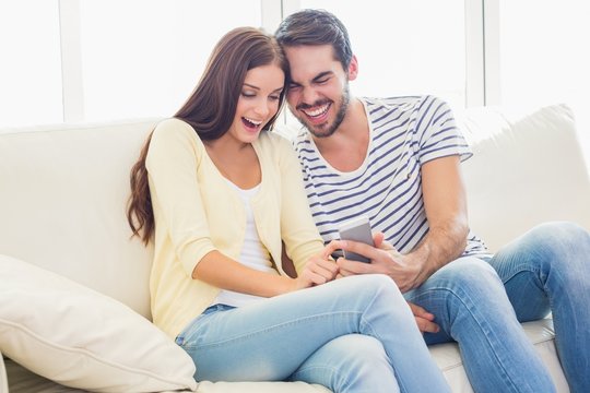 Cute couple relaxing on couch with smartphone