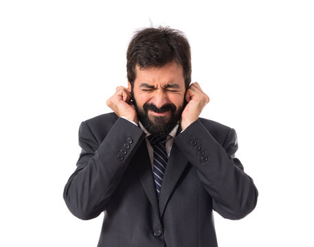 Businessman covering his ears over white background