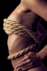 Fototapeta na wymiar gefesselte devote und nackte Frau, stehend mit einem Seil, vinta