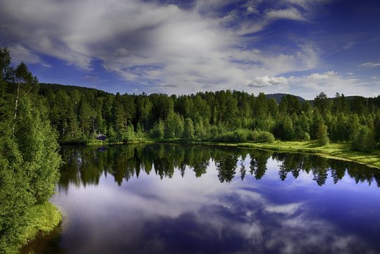 Calm lake reflection against the blue sky with white clouds