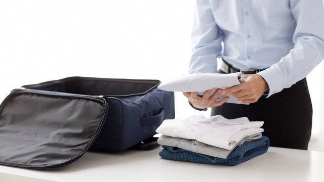 businessman packing clothes into travel bag