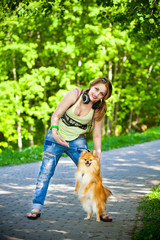 girl in shirt and jeans outdoors with her dog Spitz