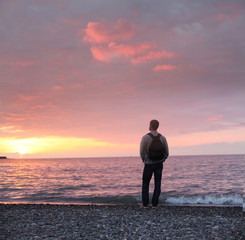alone man looking at the sunset on a beach