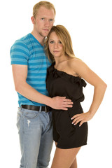 man in blue shirt arms around woman both looking