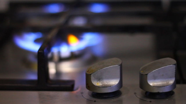 Turns on gas stove with burning flame
