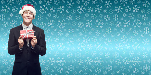 young business man in santa hat holding christmas gift over wint