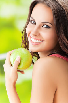 Young woman with green apple, outdoors