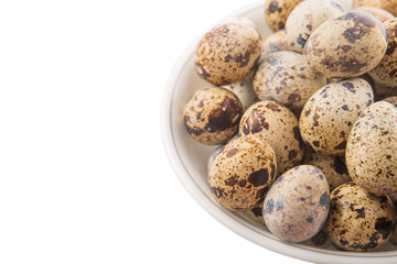 Quail eggs in a white bowl over white background 