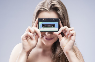 Young Caucasian Blond Woman Holding Audio Cassette In Front