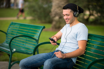 Obraz premium Young male using his cell phone in the park