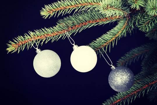Three christmas balls hanging on a twig.