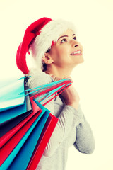 Beautiful woman in santa hat carrying shopping bags.