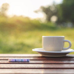 Holiday written in letter beads and a coffee cup on table