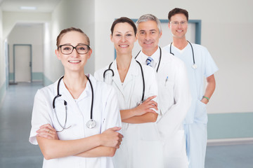 Doctors With Arms Crossed Standing In Row At Hospital Corridor