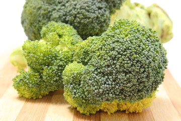 Portion of fresh green broccoli on wooden cutting board