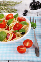 Spaghetti with tomatoes, olives and basil leaves